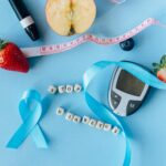 Creative diabetes awareness with fruits, glucometer, and ribbon on blue background.