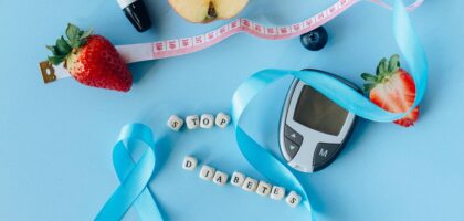 Creative diabetes awareness with fruits, glucometer, and ribbon on blue background.