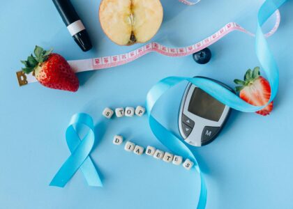 Creative diabetes awareness with fruits, glucometer, and ribbon on blue background.