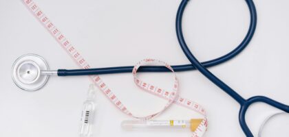 A stethoscope, ampoule, and tape measure on a white background symbolize healthcare essentials.