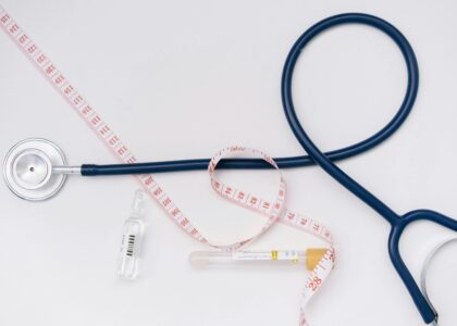 A stethoscope, ampoule, and tape measure on a white background symbolize healthcare essentials.